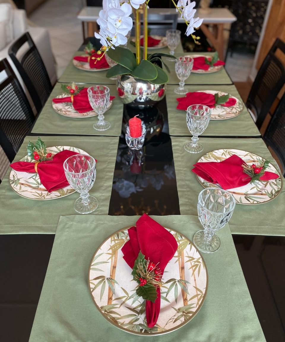 Mesa posta completa com caminho de mesa verde, guardanapos vermelhos e louça decorada